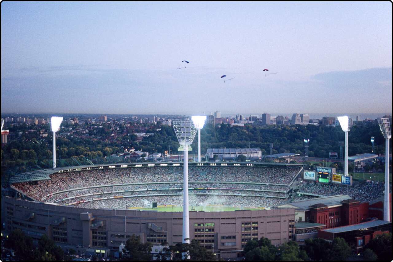 Melbourne Cricket Ground in the evening, with the city skyline visible in the background.